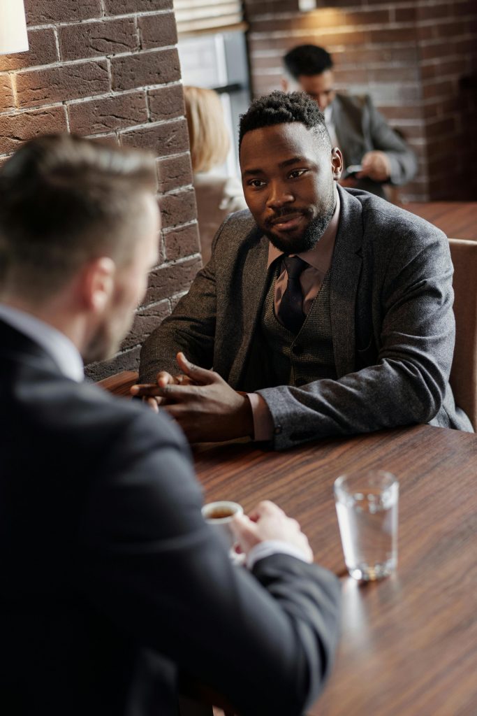 Two businessmen in suits chatting during a coffee break in a stylish café.